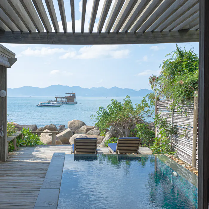 Timber decking and loungers along the edge of a pool.