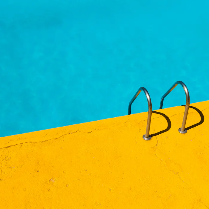 A stainless steel ladder descending into clear pool water.