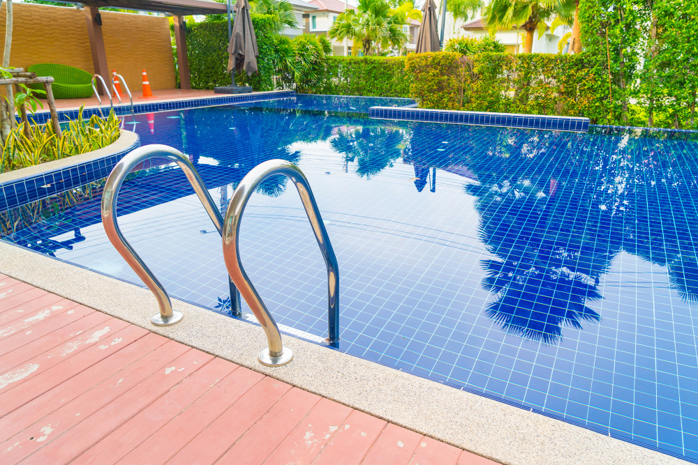 A pool finished in deep blue mosaic tiles with a steel ladder at the edge.