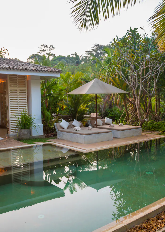 A rectangular swimming pool beside a private house and terrace.