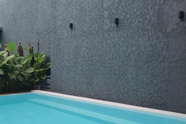 A raised pool edge meeting a rendered retaining wall.